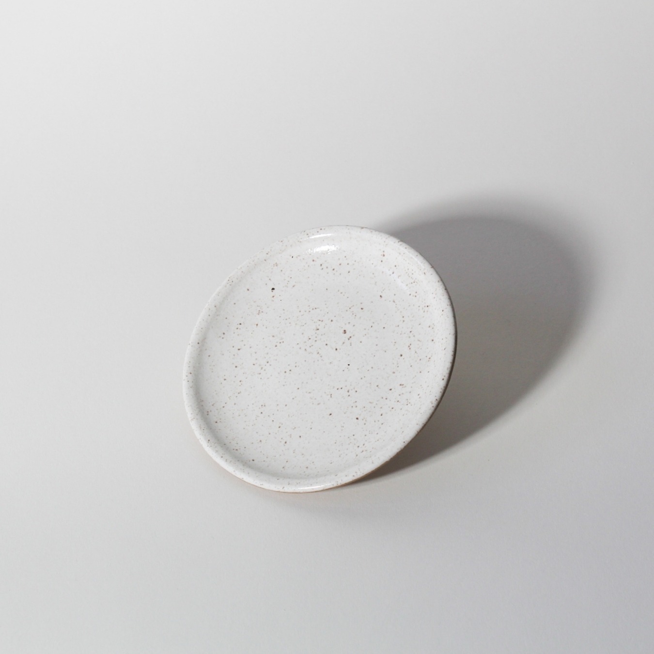 Pires de cerâmica branco Esmo com base em argila tabaco sobre fundo neutro inclinado frontal.