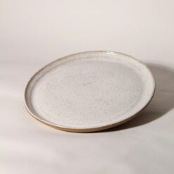 Prato de cerâmica esmaltada branco salpicado com borda em argila tabaco natural e silhueta plana. By Esmo.
