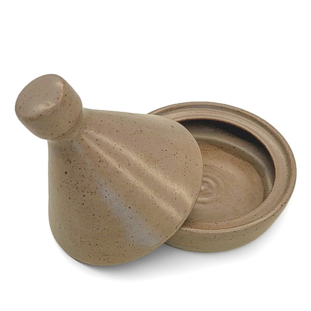 Saleiro Tagine em cerâmica na cor Oliva da Esmo, aberto. A peça exibe um esmalte verde acetinado com denso pontilhado orgânico escuro, revelando o interior côncavo do recipiente e a tampa cônica apoiada ao lado.