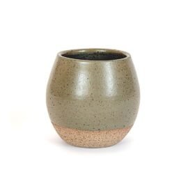 Copo Esmo de cerâmica na cor Oliva, apresentando formato arredondado com base em argila natural texturizada e topo em esmalte verde sóbrio acetinado com denso pontilhado orgânico escuro, sobre fundo branco.