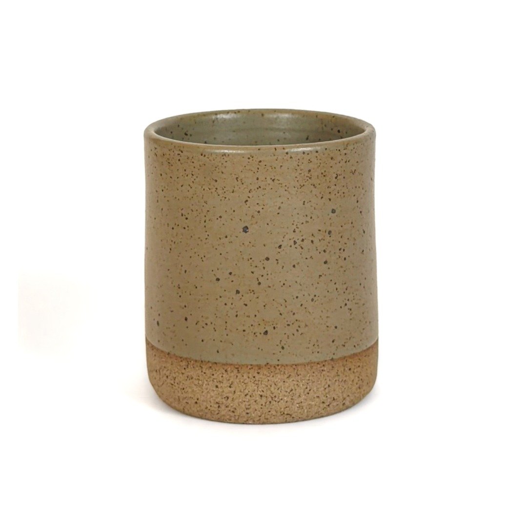 Um copo de cerâmica de silhueta reta e minimalista, de 240ml da Esmo Cerâmica, em fundo branco. A peça possui um esmalte verde Oliva acetinado e denso pontilhado orgânico no corpo, contrastando com a base em cerâmica crua de argila tabaco.