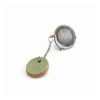 O infusor de chá com Tag Redonda em Cerâmica Artesanal da Esmo (3cm) ganha frescor na edição Pistache. Uma peça utilitária que funciona como contrapeso estratégico na xícara, destacando a dualidade visual entre o esmalte verde suave e a rusticidade natural da matéria exposta na base.