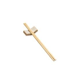 Porta-Hashi de cerâmica na cor Off-White com esmalte claro e pontinhos escuros na superfície superior, contrastando com a base e as laterais em argila rústica aparente. A peça possui formato retangular curvo, servindo de suporte para um par de hashis de madeira cruzados e dispostos sobre ela, em fundo branco.