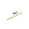 Porta-Hashi da Esmo, de cerâmica na cor Off-White com esmalte claro e pontinhos escuros na superfície superior, contrastando com a base e as laterais em argila rústica aparente. A peça possui formato retangular curvo, servindo de suporte para um par de hashis de madeira cruzados e dispostos sobre ela, em fundo branco.
