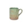 Caneca Reta em Cerâmica Artesanal n na cor Verde Pistache Pistache da Esmo. A peça apresenta um contraste evidente: os dois terços superiores possuem esmalte vitrificado verde suave com um sutil pontilhado orgânico escuro, enquanto a base inferior revela a cerâmica crua com textura rústica e terrosa. Alça esmaltada na lateral direita.