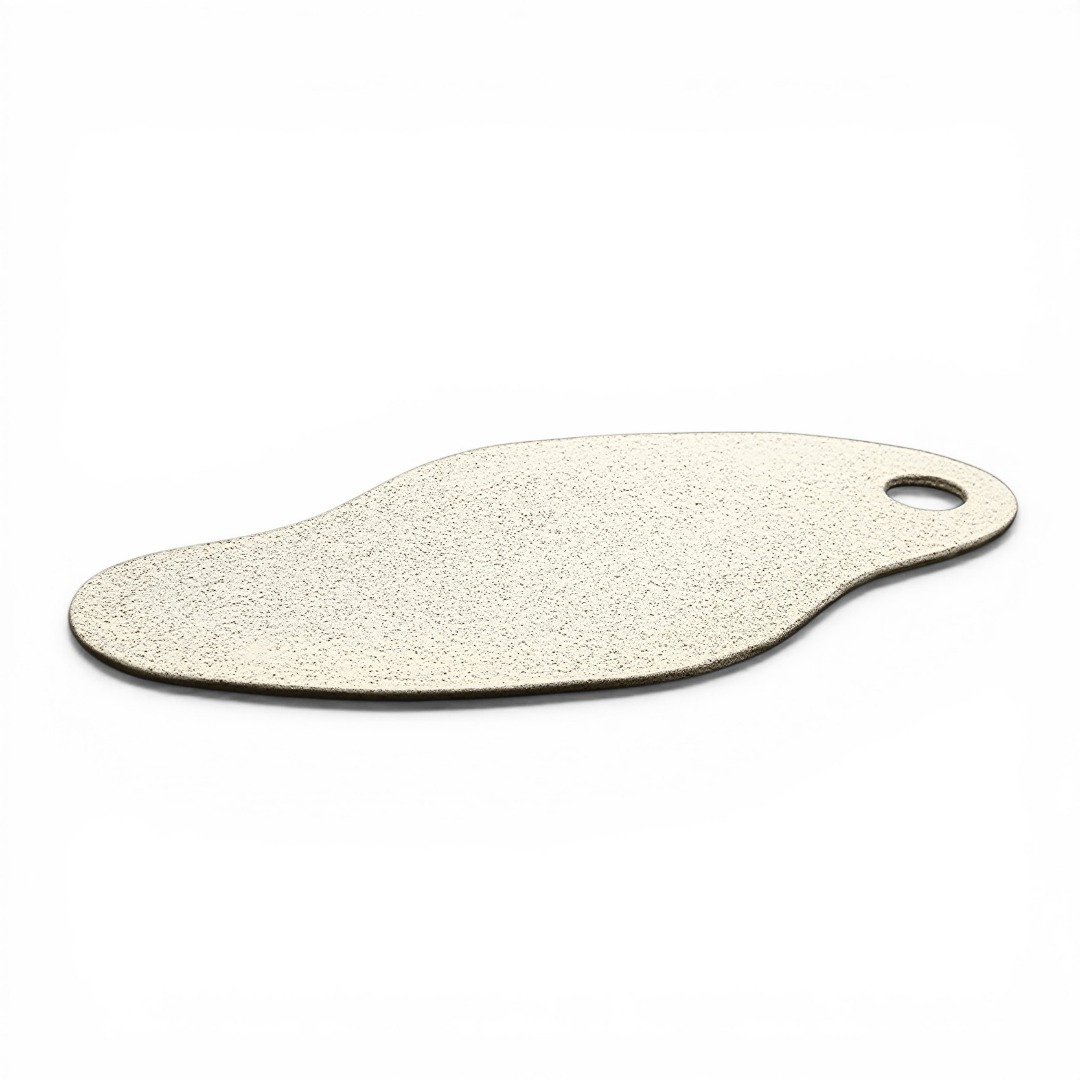 Tábua Linear plana em cerâmica na cor Off-White, com acabamento mate e textura orgânica levemente pontilhada, apresentando silhueta minimalista e um orifício ergonômico em uma das pontas, vista em perspectiva sobre fundo branco.