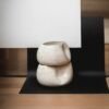 Composição com dois Centros de Mesa Alto Grande na cor Off-White de cerâmica empilhados, evidenciando o contraste da silhueta orgânica irregular e o acabamento salpicado suave contra um fundo geométrico e minimalista.