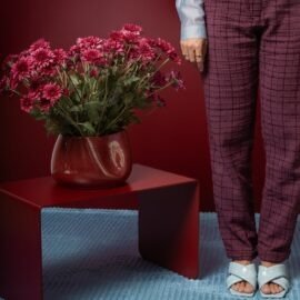 Centro de Mesa Alto Grande da Esmo Cerâmica na cor Borgonha repleto de flores rosas, ambientado sobre uma mesa vermelha de design moderno.