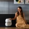A designer e fundadora da Esmo, Bruna Vuelma, ao lado de dois Centros de Mesa Alto empilhados, demonstrando a volumetria imponente, a ergonomia visual e a proporção das peças em cerâmica texturizada.