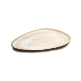 Prato Sushi Gota na cor Off-White, uma autêntica peça de cerâmica artesanal da Esmo. A imagem captura o produto em um ângulo levemente superior, evidenciando sua silhueta orgânica e assimétrica que remete à forma de uma gota. A incidência de luz difunde suavemente sobre o acabamento mate e acetinado da superfície, ressaltando uma textura visual extremamente sutil e limpa. A borda revela o contraste tátil da cerâmica rústica aparente, gerando uma discreta sombra projetada que enfatiza a presença plana, funcional e arquitetônica do design.