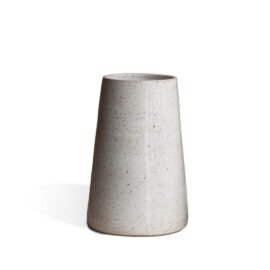Vaso Cônico Intermediário na cor Off-White da Esmo. A peça decorativa em cerâmica artesanal possui formato afunilado de linhas precisas. O acabamento mate interage de forma suave com a incidência de luz, evidenciando uma textura sutil com delicados pontilhados na superfície clara. A margem inferior exibe um fino detalhe em cerâmica rústica, criando um contraste sóbrio com a luminosidade do esmalte e projetando uma leve sombra lateral sobre um fundo neutro.