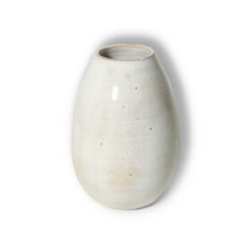 Vaso Oval Intermediário na cor Off-White da Esmo, exibindo sua proporção ampliada e formato elíptico elegante contra um fundo limpo. A peça de cerâmica artesanal é banhada por uma luz suave que destaca seu acabamento mate e acetinado, revelando minúsculas pintinhas orgânicas na superfície clara. A luminosidade neutra do esmalte valoriza a curvatura orgânica do design, criando um sutil degradê de sombras que confere volume e presença à peça. A borda superior, perfeitamente circular, delimita a abertura do vaso de forma limpa e estruturada.