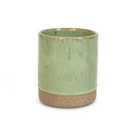Copo Reto Grande de cerâmica na cor Pistache da Esmo. A peça cilíndrica apresenta um forte contraste visual: a parte superior é coberta por um esmalte verde suave vitrificado com pontilhado orgânico, enquanto a base na parte inferior revela a textura rústica e áspera da argila exposta.