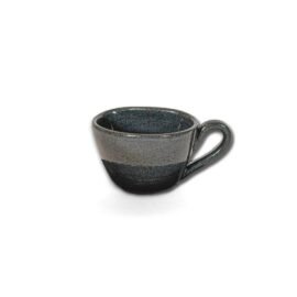 Xícara Orgânica Expresso na cor Cinza da Esmo Cerâmica. A peça possui formato sutilmente irregular com alça ergonômica, evidenciando uma forte divisão de texturas: a metade superior apresenta acabamento esmaltado escuro com pontos naturais que refletem a luz, enquanto a base revela a textura da cerâmica crua e rústica sem esmalte.