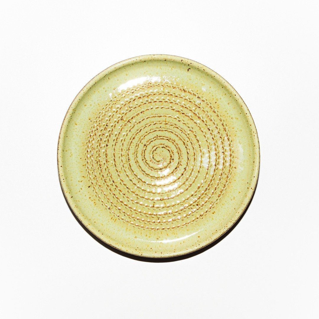 Vista superior do Prato Ralador de cerâmica da Esmo no tom Matcha Latte. Mostra o formato circular com relevo espiralado para triturar alimentos, acabamento brilhante e leitoso com sardas da massa e borda contida em cerâmica.